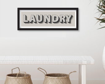 May include: A black framed print with the word "LAUNDRY" in white letters with black polka dots on a light gray background. Three woven baskets sit on a white bench in front of the print.