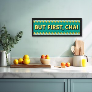 May include: A teal and yellow framed sign with the text "BUT FIRST, CHAI" in a retro font.