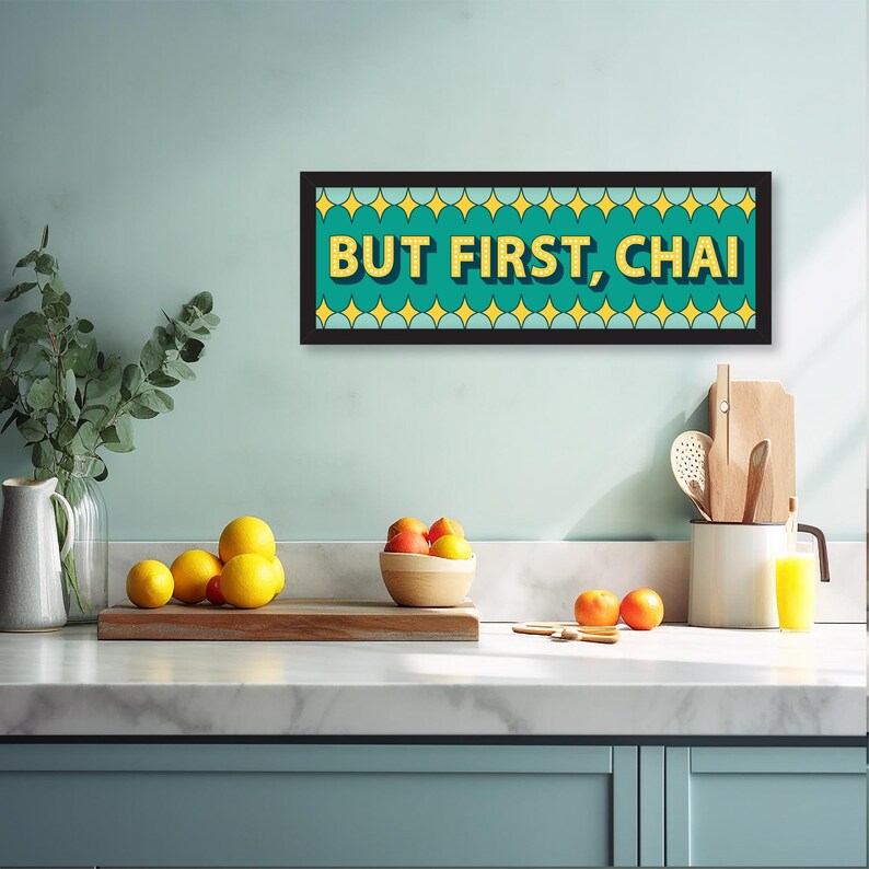 May include: A teal and yellow framed sign with the text "BUT FIRST, CHAI" in a retro font.