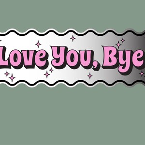 以下が含まれることがあります： 波型の縁取りと、黒いアウトラインのピンク色のバブルレターで「Love You, Bye」という言葉が書かれた長方形のステッカー。ステッカーはシルバーのグラデーションの背景とピンクの星のアクセントがあります。