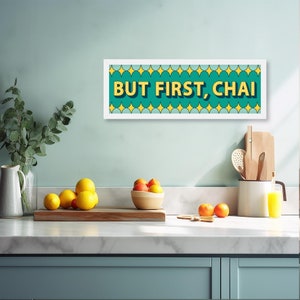 May include: A white framed print with a teal background and yellow text that reads "BUT FIRST, CHAI". The text is outlined in black and has a glittery effect. The background is decorated with a pattern of yellow stars.