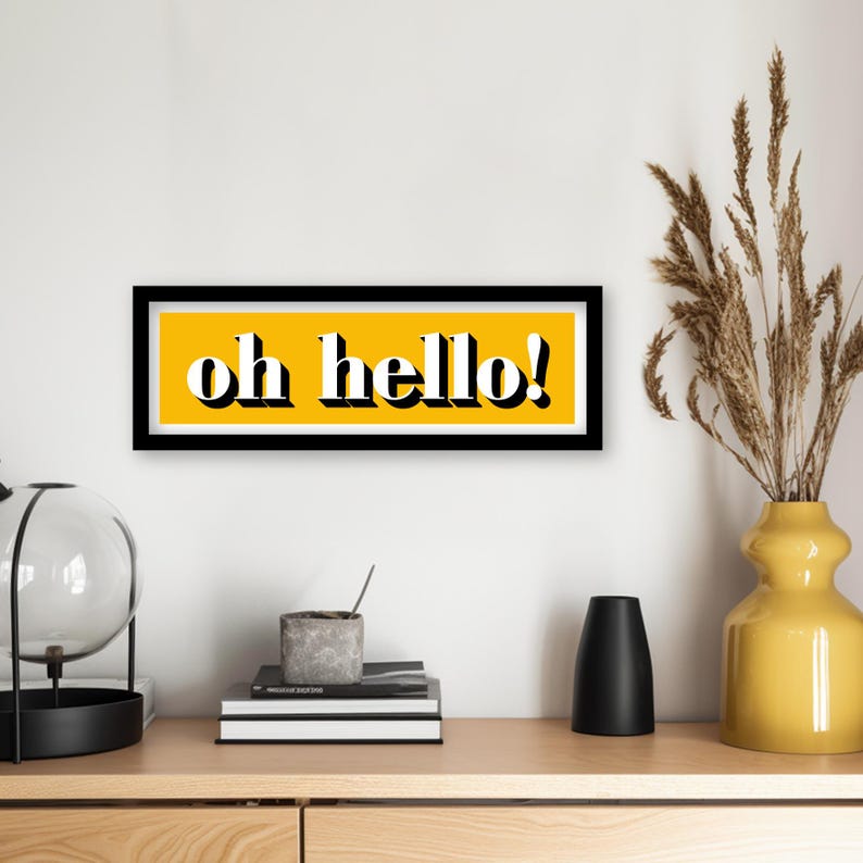 May include: A black framed print with a yellow background and the text "oh hello!" in white letters.