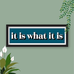 Könnte beinhalten: Ein türkisfarbenes Schild mit dem Text "it is what it is" in weißen Buchstaben mit schwarzem Umriss. Das Schild hängt an einer hellgrünen Wand.