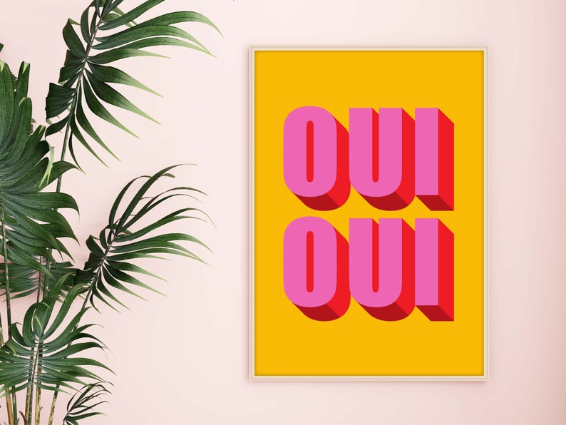 May include: A framed print with a yellow background and the word "OUI" written in pink letters with a 3D effect.