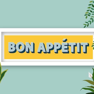 May include: A white framed sign with a yellow background and the text "BON APPÉTIT" in blue with white dots around the letters.