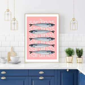 Op de afbeelding: Een roze en witte print met het woord "sardines" dat zes keer wordt herhaald. Elk woord is overlegd met een tekening van een sardinesvis.