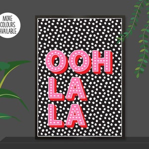 以下が含まれることがあります： 黒と白のドット柄に「ooh la la」というピンクの文字が書かれたプリント。文字は3D効果があり、赤で縁取られています。
