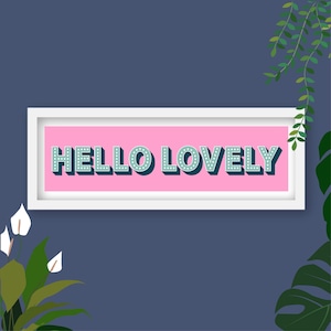 Peut inclure: Un cadre blanc avec un fond rose et le texte "HELLO LOVELY" en turquoise avec des pois blancs. Le cadre est entouré de plantes vertes.