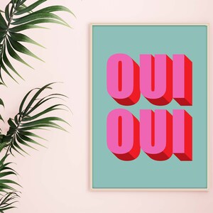 May include: A framed print with a teal background and the word "OUI" written twice in pink and red 3D letters.