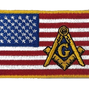 Peut inclure: Un patch brodé représentant le drapeau américain avec un symbole maçonnique doré dans le coin inférieur droit. Le symbole est un carré et un compas avec un 'G' au centre.