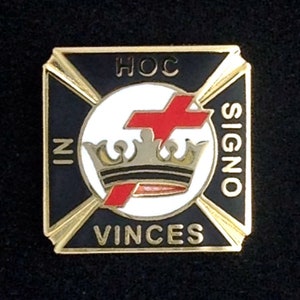 May include: A gold and black square pin with a white circle in the centre. The circle features a red cross over a gold crown. The text "HOC IN SIGNO VINCES" surrounds the circle.