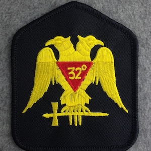 May include: A black embroidered patch with a yellow double-headed eagle, a red triangle with the number "32°" inside, and a yellow sword and cross.