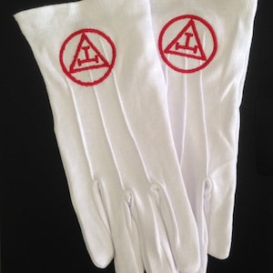 May include: A pair of white cotton gloves with red embroidered Masonic symbols on the back of each glove.