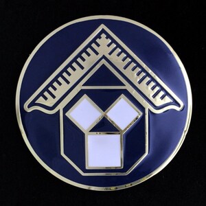 May include: A gold and white Masonic emblem on a blue background. The emblem features a square and compass with a stylized cube in the center.