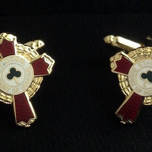 May include: A pair of gold cufflinks with a red enamel cross and a white circle with a black shamrock and the text "KNIGHTS OF COURT OF HONOUR".