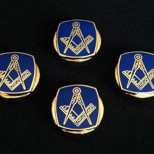 May include: Four gold-colored cufflinks with a blue enamel square design featuring a compass and square, a symbol of Freemasonry.