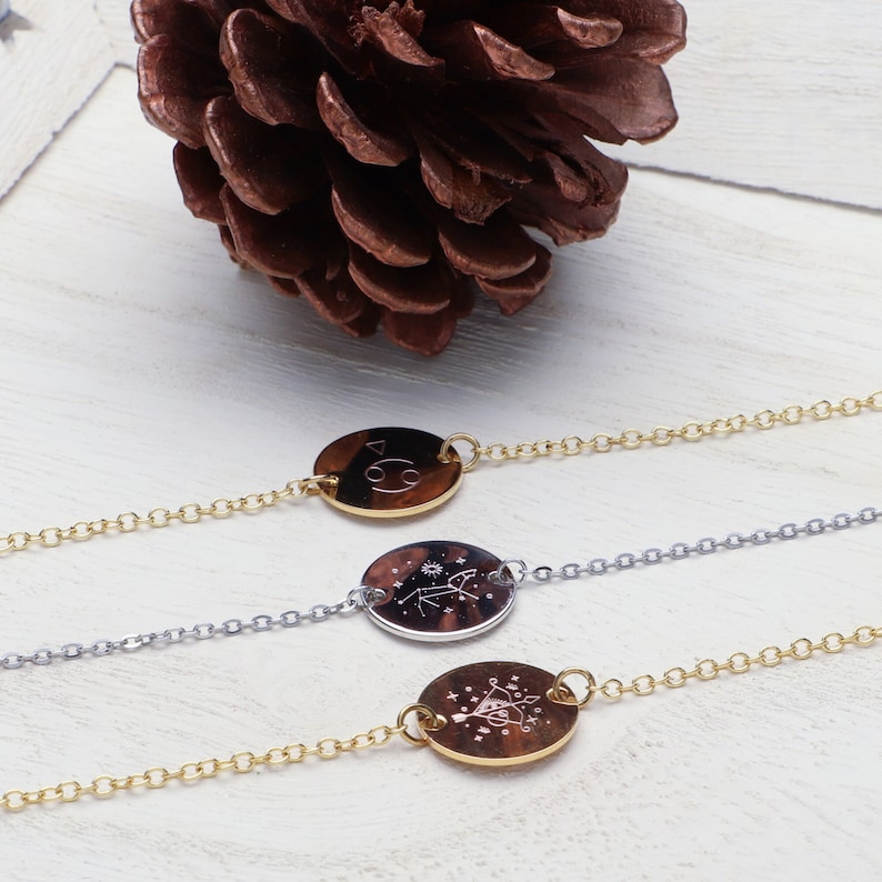 Peut inclure: Trois bracelets en cha&icirc;ne dor&eacute;e avec des pendentifs ronds repr&eacute;sentant des signes du zodiaque. Les pendentifs sont grav&eacute;s avec les symboles du Cancer, du Sagittaire et des G&eacute;meaux.