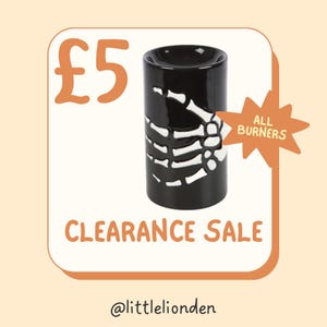 May include: Black ceramic oil burner featuring a white skeleton hand design. The image includes the text "CLEARANCE SALE" in orange, and the text "ALL BURNERS".
