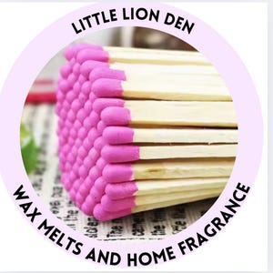 May include: A close-up of a bundle of pink-tipped wooden matches. The matches are arranged in a square shape and are labelled "Little Lion Den Wax Melts and Home Fragrance".