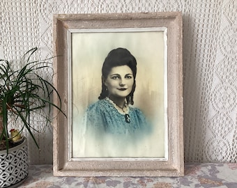 May include: A framed black and white photograph of a woman in a blue dress. The frame is white with a distressed finish.