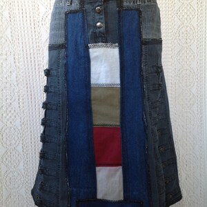 K&ouml;nnte beinhalten: Ein Jeansrock mit Patchwork-Design. Der Rock besteht aus verschiedenen Blaut&ouml;nen von Jeans und hat ein Einsatz aus wei&szlig;em, gr&uuml;nem und rotem Stoff. Der Rock hat einen Knopfverschluss und eine ausgestellte Silhouette.
