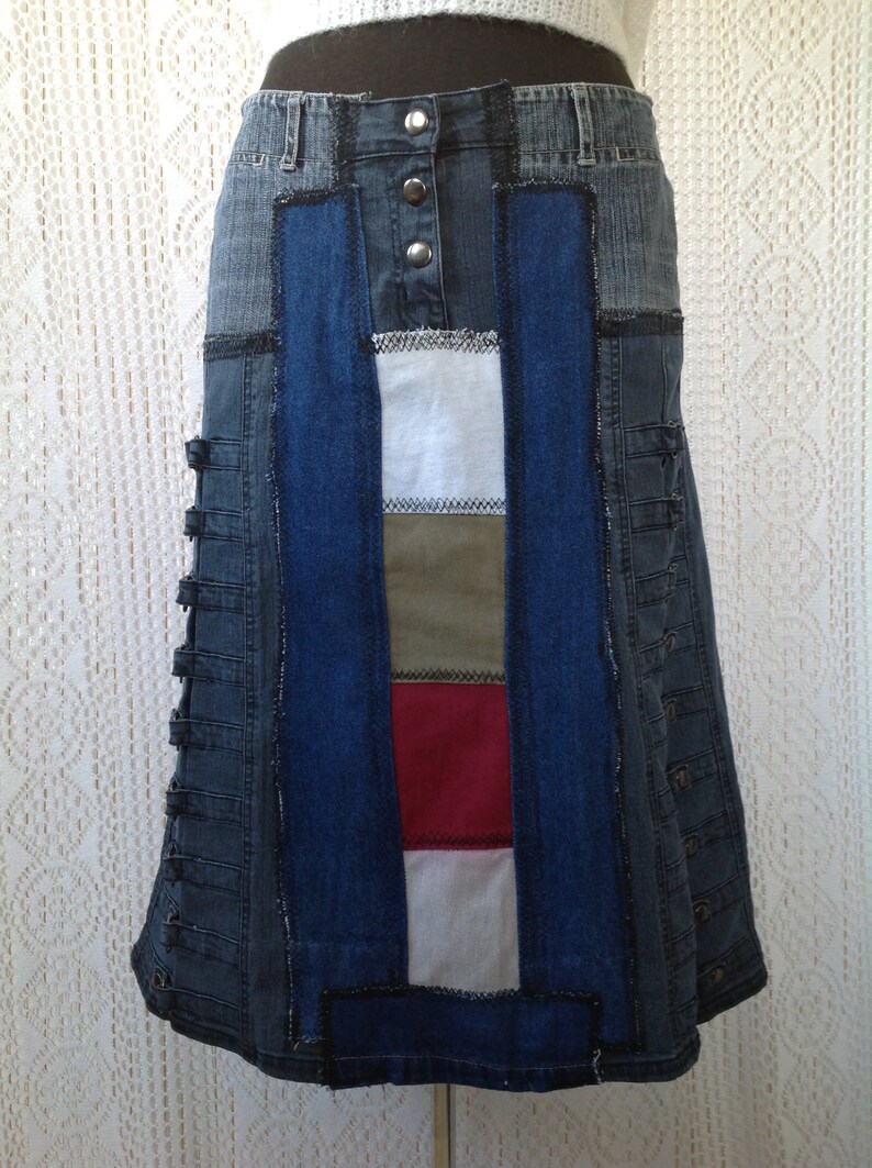 K&ouml;nnte beinhalten: Ein Jeansrock mit Patchwork-Design. Der Rock besteht aus verschiedenen Blaut&ouml;nen von Jeans und hat ein Einsatz aus wei&szlig;em, gr&uuml;nem und rotem Stoff. Der Rock hat einen Knopfverschluss und eine ausgestellte Silhouette.