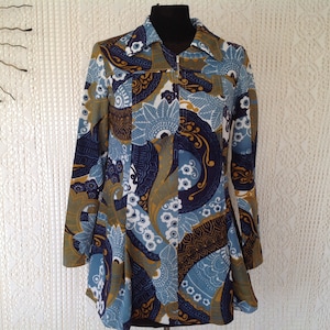 Peut inclure: Une veste à manches longues avec un motif paisley bleu, blanc et or. La veste a une fermeture éclair et un col.