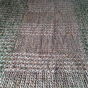 Peut inclure: Gros plan sur un tissu tricoté avec un motif vert et gris. Le tissu est fait d'un fil doux et texturé et présente un motif de points diagonaux.
