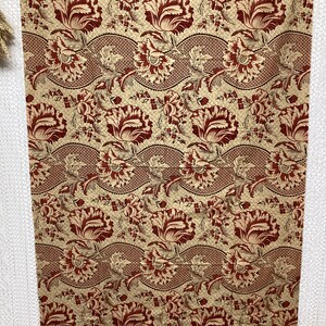 May include: Red and gold floral fabric with a repeating pattern of stylized flowers and leaves. The fabric has a textured, woven look.
