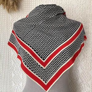 May include: A square scarf with a patriotic design. The scarf features a pattern of white stars on a navy blue background, framed by red and off-white stripes. The scarf is displayed on a mannequin.