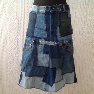 Puede incluir: Una falda vaquera hecha de piezas de mezclilla azul patchwork en varios tonos. La falda tiene una silueta acampanada y un dobladillo sin rematar.