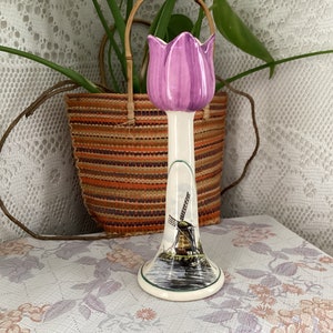May include: A ceramic tulip-shaped candle holder with a purple tulip on top and a painted windmill scene on the base.