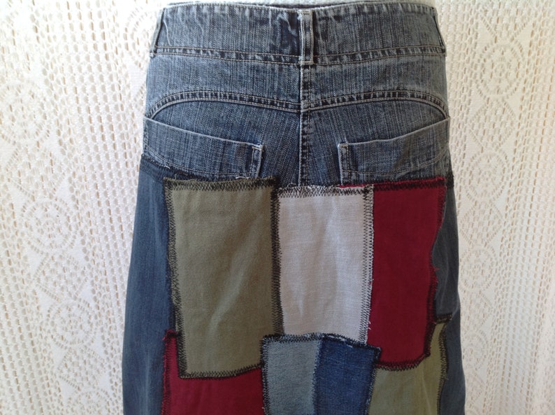 K&ouml;nnte beinhalten: Ein Jeansrock mit Patchwork-Design. Der Rock besteht aus verschiedenen Stoffen in den Farben Blau, Gr&uuml;n, Rot und Wei&szlig;. Der Rock hat eine hohe Taille und eine gerade Silhouette.