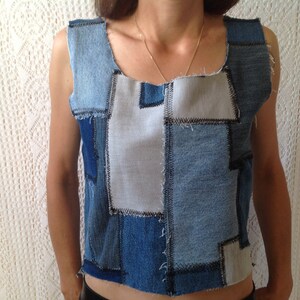 Peut inclure: Un top sans manches en denim patchwork. Le haut est un mélange de denim bleu clair et foncé avec un peu de tissu blanc. Les coutures sont visibles et ont un bord brut.