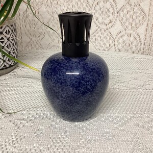 May include: A blue speckled ceramic fragrance lamp with a black top. The lamp has a rounded body and a decorative design. The lamp is a home decor item.
