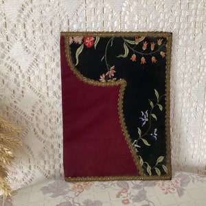 Peut inclure: Textile rectangulaire à deux tons, avec une base bordeaux et un recouvrement noir brodé de fleurs. La section noire présente une broderie florale colorée et est bordée d'une garniture dorée. Il s'agit probablement d'un article décoratif.