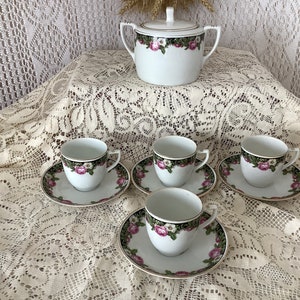 Puede incluir: Juego de té de porcelana blanca con diseño de rosas florales. El juego incluye cuatro tazas y platillos, y una azucarera con tapa. Los bordes de las tazas, platillos y azucarera están adornados con oro.