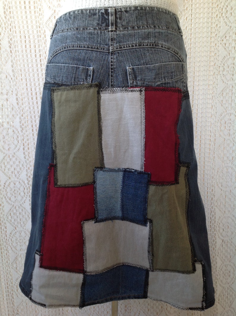 K&ouml;nnte beinhalten: Ein Jeansrock mit Patchwork-Design. Der Rock besteht aus verschiedenen farbigen Jeans- und Stoffresten, darunter Rot, Blau, Gr&uuml;n und Grau. Der Rock hat eine hohe Taille und eine ausgestellte Silhouette.