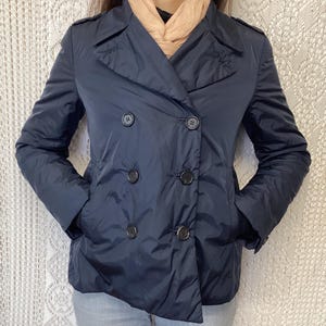 Peut inclure: Une veste bleu foncé à double boutonnage avec une fermeture éclair et plusieurs poches.