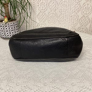 Pu&ograve; includere: Borsa in pelle nera con finitura strutturata e cuciture bianche. La borsa ha una forma arrotondata e una cerniera superiore. Il fondo della borsa &egrave; visibile, mostrando la pelle strutturata e le cuciture.