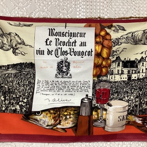 May include: A vintage kitchen towel with a red border features a black and white illustration of a fish, a glass of red wine, a salt shaker, and a pitcher. The text on the towel reads "Monseigneur Le Brochet au vin de Clos-Vougeot" and is signed "F. Oliver".