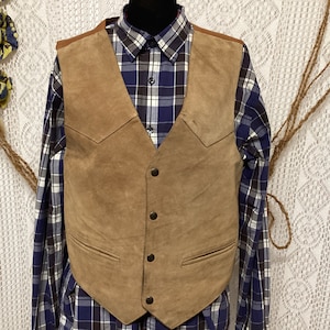 Peut inclure: Un gilet en daim marron avec une fermeture à boutons et deux poches. Le gilet a un style western classique.