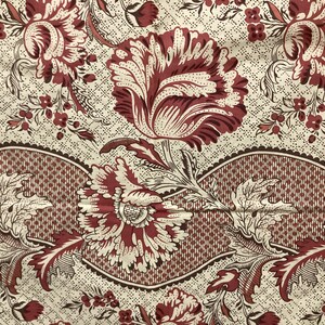 May include: A vintage fabric with a repeating pattern of red and white flowers on a cream background. The flowers have a detailed design and are surrounded by smaller floral motifs. The fabric has a woven texture and a slightly faded appearance.