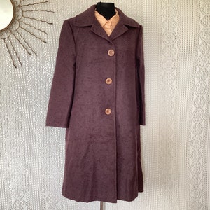 May include: A long, dark purple wool coat with a collar and five buttons down the front.