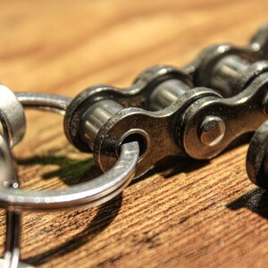 May include: A silver key chain with a silver chain link attached to a silver ring. The chain link is made of metal and has a shiny finish.