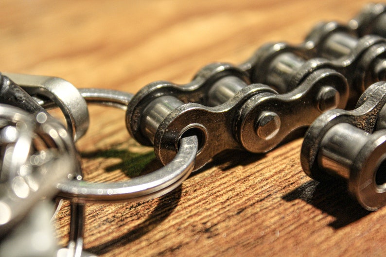May include: A silver key chain with a silver chain link attached to a silver ring. The chain link is made of metal and has a shiny finish.