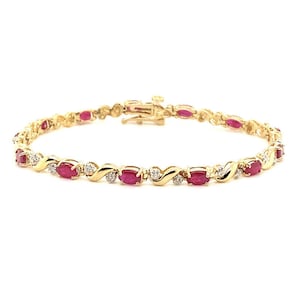 May include: A gold bracelet with oval-cut red gemstones and small, round, clear gemstones. The bracelet has a clasp closure and a delicate design. The gemstones are set in a repeating pattern along the length of the bracelet.