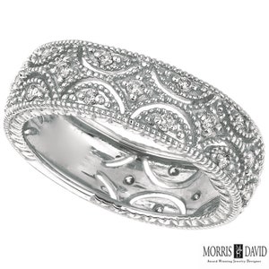 May include: A silver band ring with a delicate, intricate design featuring small diamonds set in the metal. The ring has a rounded shape and a smooth, polished finish.