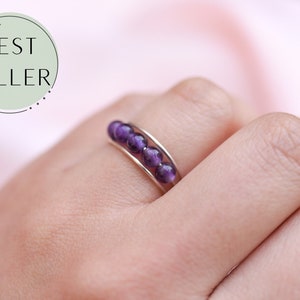 May include: A silver ring with a row of six purple amethyst beads.