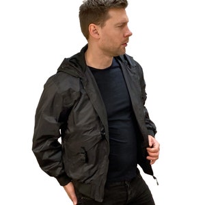 May include: A black hooded jacket with a zipper closure and a buckle detail on the front pocket.